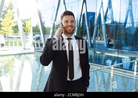 Businessman Talking on Phone Isolated. Business man Standing Full Length with Phone in Hand Stock Photo