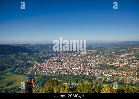 Aerial view over the town of Millau with the famous Millau Viaduct or Viaduc de Millau in the far distance. A blue sky overhead in Aveyron, France Stock Photo