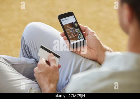 Close-up of young man using mobile phone to order food delivery he paying with credit card Stock Photo