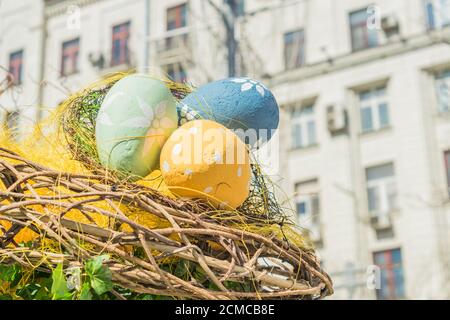 wooden nest with three multicolored eggs. Painted easter decoration outdoors Stock Photo