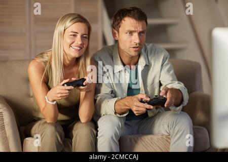 Young smiling couple having fun while playing in computer game at home Stock Photo