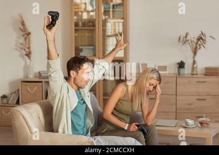 Young man winning the game while playing with his girlfriend they sitting on sofa in the living room at home Stock Photo