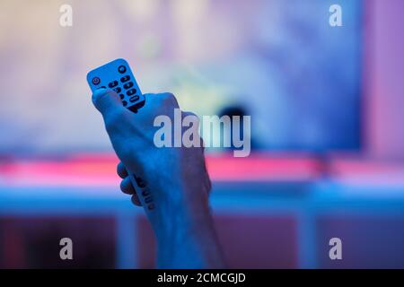 Close-up of man holding remote control during watching TV at home Stock Photo