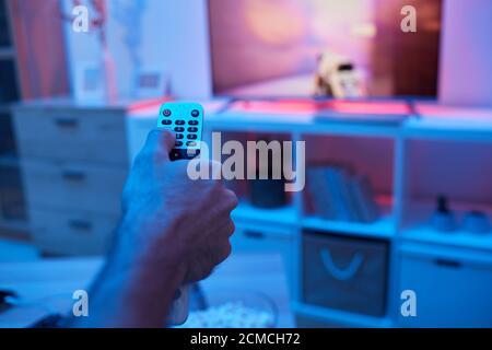 Close-up of man using remote control and changing the channels during watching TV Stock Photo