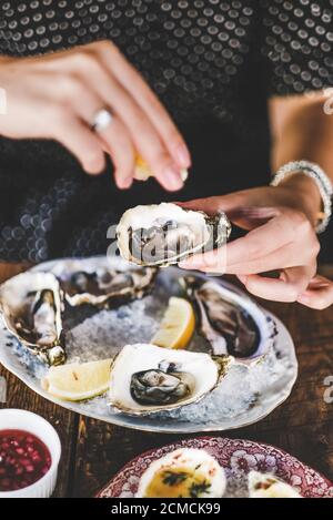 Woman squeezing lemon juice to fresh Irish oysters Stock Photo