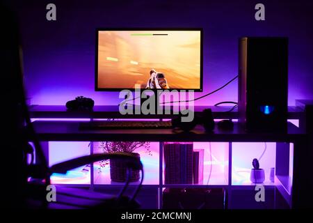 Image of computer monitor with game on it on the table with bright light in dark room Stock Photo