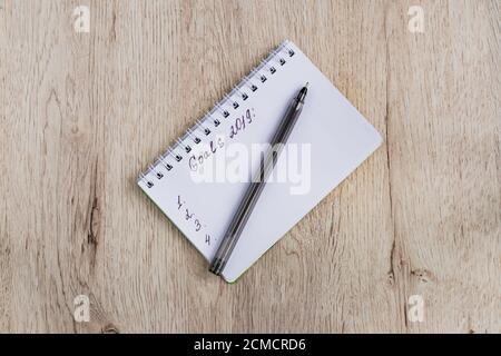 Business and office concept - blank notebook and black pen on wooden table. Goals 2019. Minimal flat lay, top view. Stock Photo