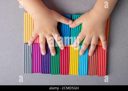 Kids hands holding colorful plasticine on grey table Stock Photo