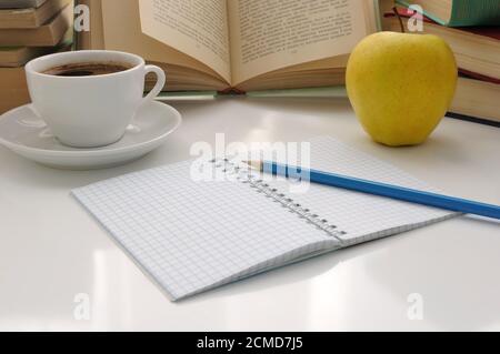 Notebook with a pencil on a table with a cup of coffee and an apple with books Stock Photo
