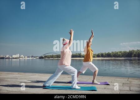 Two people doing the warrior one pose Stock Photo