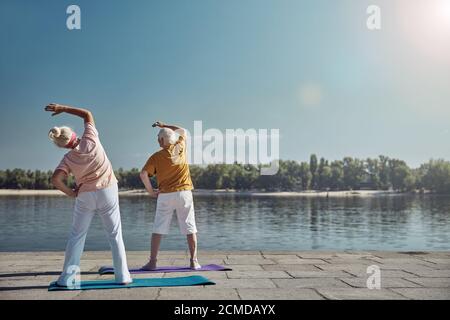Two senior people stretching her oblique muscles Stock Photo
