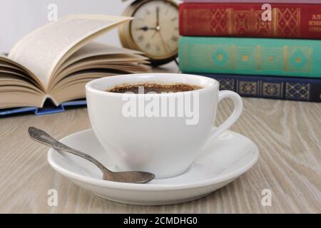 A cup of coffee on the table against the background of an open book Stock Photo