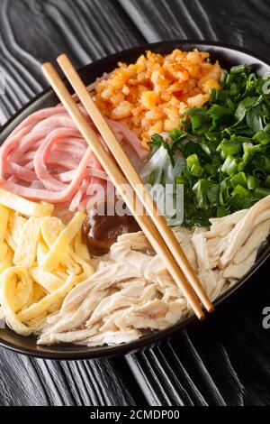 Vietnamese Bun thang Hanoi rice vermicelli noodles with chicken, eggs and pork is a sophisticated soup closeup in the plate on the table. Vertical Stock Photo