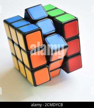 An isolated Rubik's Cube puzzle sits almost solved on a crisp white background in bright natural light Stock Photo