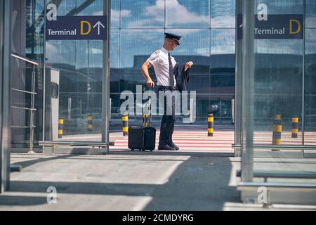 Good-looking male pilot checking time at airport Stock Photo