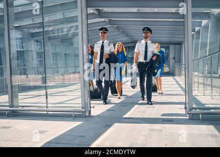 Aircrew with travel suitcases walking in airport terminal Stock Photo