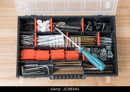 Open toolbox with different instruments. Screws and screwdriver Plactic box with tools on wooden background. Furniture assembly and renovation work Stock Photo