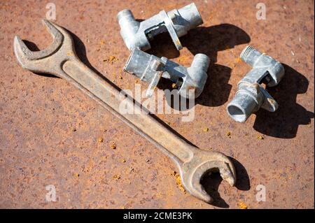 Old wrench and metal parts on a rusty sheet of metal, close-up, selective focus Stock Photo