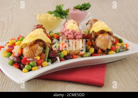 Chicken leg wrapped in bacon with vegetables and different sauces Stock Photo