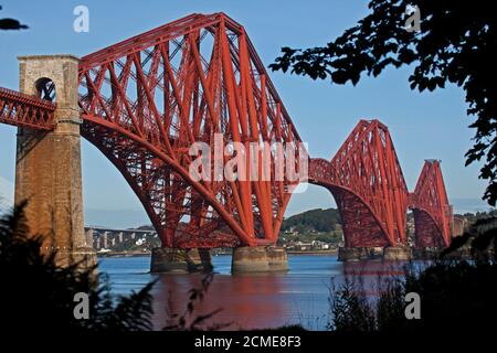 South Queensferry, Edinburgh, Scotland, UK. 17 September 2020. The iconic Forth Rail Bridge bathed in sunshine framed by foliage and grass with a mid morning temperature of 14 degrees centigrade. Credit: Arch White/ Alamy Live News. Stock Photo