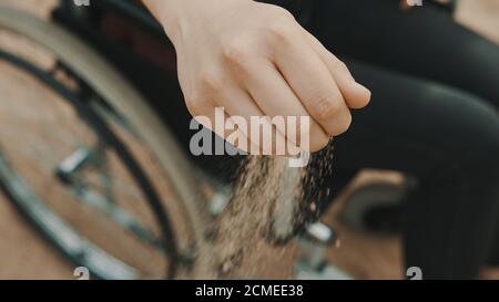 close up, hand of disabled person in the wheelchair playing with the sand on the beach. High quality photo Stock Photo