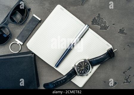 Businessman's accessories including notepad, watch and purse on dark grey background Stock Photo