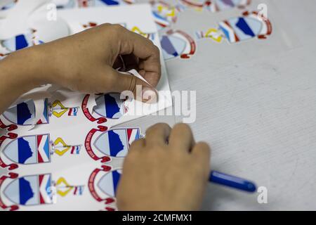 Kota Kinabalu, Sabah, Malaysia-August 15, 2020 : Female worker hand on peel sticker in Textile Industry at Garment Manufacturers Stock Photo