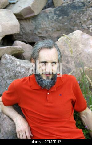 bearded happy man sitting in a green background on sunny day, potrait Stock Photo