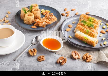 Set of various traditional arabic sweets: baklava, kunafa, basbus in  ceramic plates on a gray concrete background. top view, flat lay. Stock Photo