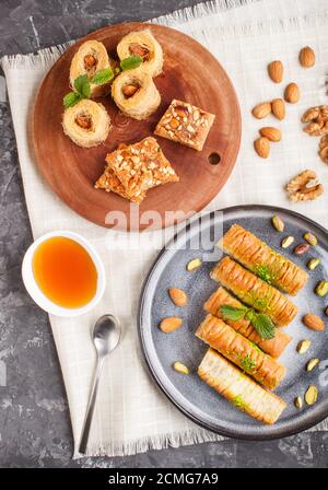 Set of various traditional arabic sweets: baklava, kunafa, basbus in  ceramic plates on a black concrete background. top view, flat lay. Stock Photo