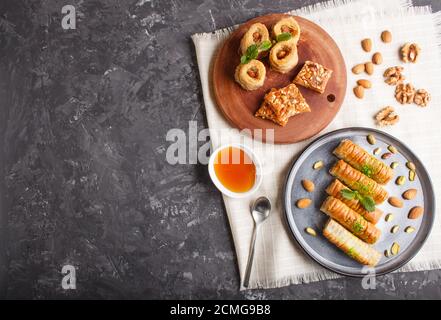 Set of various traditional arabic sweets: baklava, kunafa, basbus in  ceramic plates on a black concrete background. top view, copy space. Stock Photo