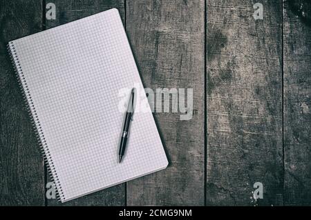 Open notebook into the cell, clean sheets lying on a wooden surface Stock Photo