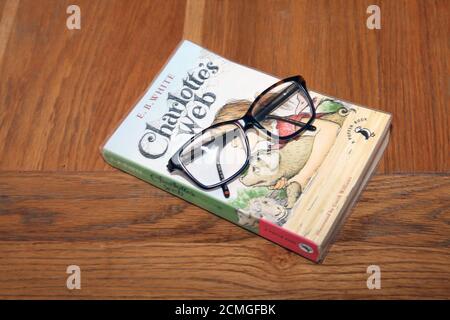 Charlotte's Webb paperback book by E.B. White with a pair of glasses on wooden table Stock Photo