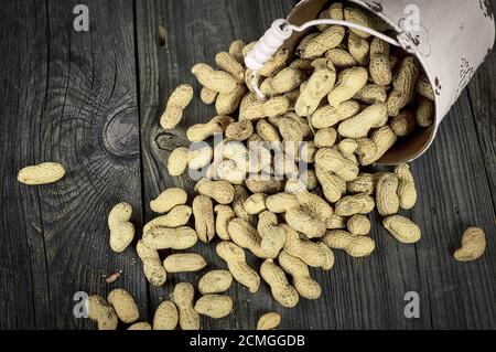 Loose peanuts in the shell on a gray wooden surface, vintage toning Stock Photo
