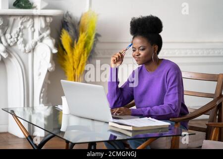 Afro-American millennial woman employee with displeased face working and looking at laptop, having operational software problems, annoyed with slow in Stock Photo