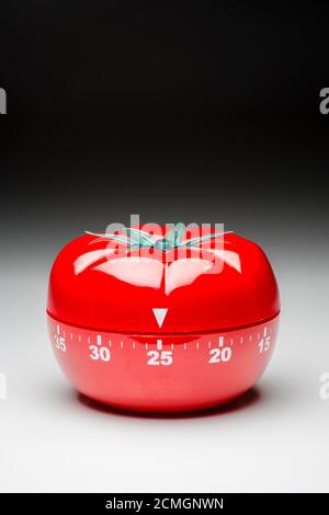 Tomato-shaped kitchen timer set at 25 minutes to fight procrastination in studying and working. Stock Photo