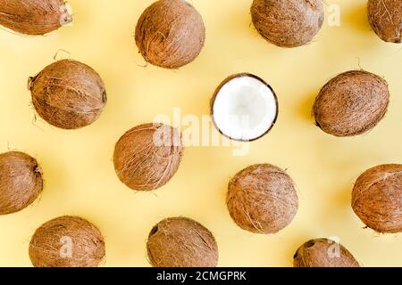 Pattern with coconuts and tropical palm leaves on yellow background. Tropical abstract background. Flat lay, top view.