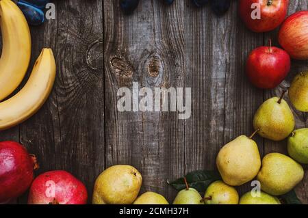 Fresh fruits on a gray wooden surface, bananas, apples, plums and pears Stock Photo