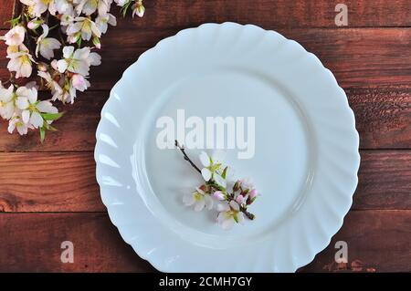 White plate on a brown wooden surface Stock Photo
