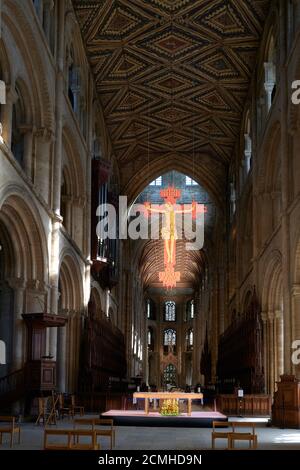 The twentieth century hanging cross of Jesus Christ crucified above the altar in the nave of the medieval built cathedral at Peterborough, England. Stock Photo