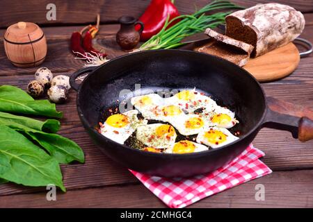 Fried quail eggs in a cast-iron black frying pan Stock Photo