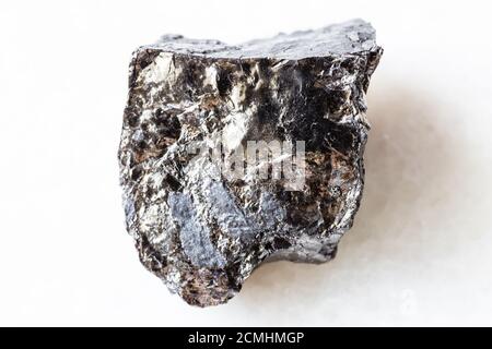 closeup of sample of natural mineral from geological collection - rough bituminous coal (black coal) on white marble background from Ukraine Stock Photo