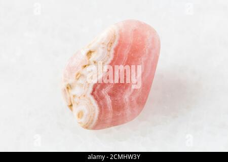 closeup of sample of natural mineral from geological collection - tumbled Rhodochrosite rock on white marble background from Argentina Stock Photo