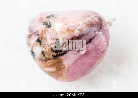 closeup of sample of natural mineral from geological collection - polished Rhodonite rock on white marble background from Tajikistan Stock Photo