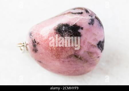 closeup of sample of natural mineral from geological collection - tumbled Rhodonite rock on white marble background from Tajikistan Stock Photo