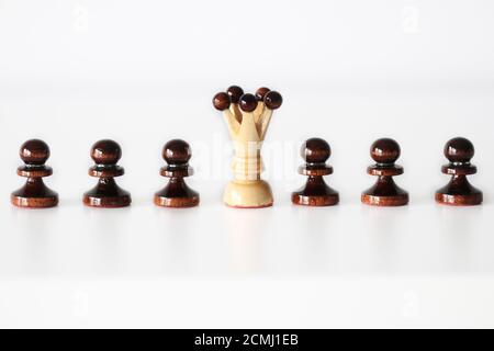 Row of black pawn chess pieces with white queen in the middle on white background - stand out of the crowd concept Stock Photo
