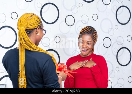 lady receiving a gift from a friend looking surprised Stock Photo