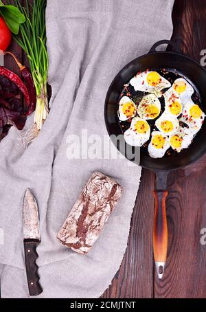 Fried quail eggs in a cast-iron black frying pan Stock Photo