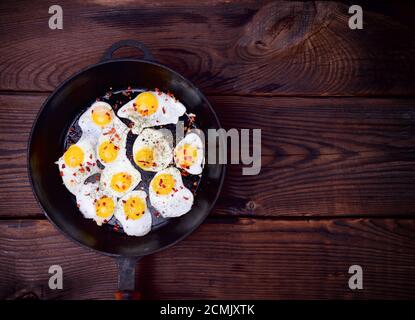 Fried quail eggs in a black cast-iron frying pan Stock Photo