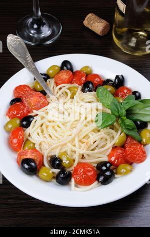 Spaghetti with olives, cherry tomatoes, sprinkled   Parmesan and basil Stock Photo